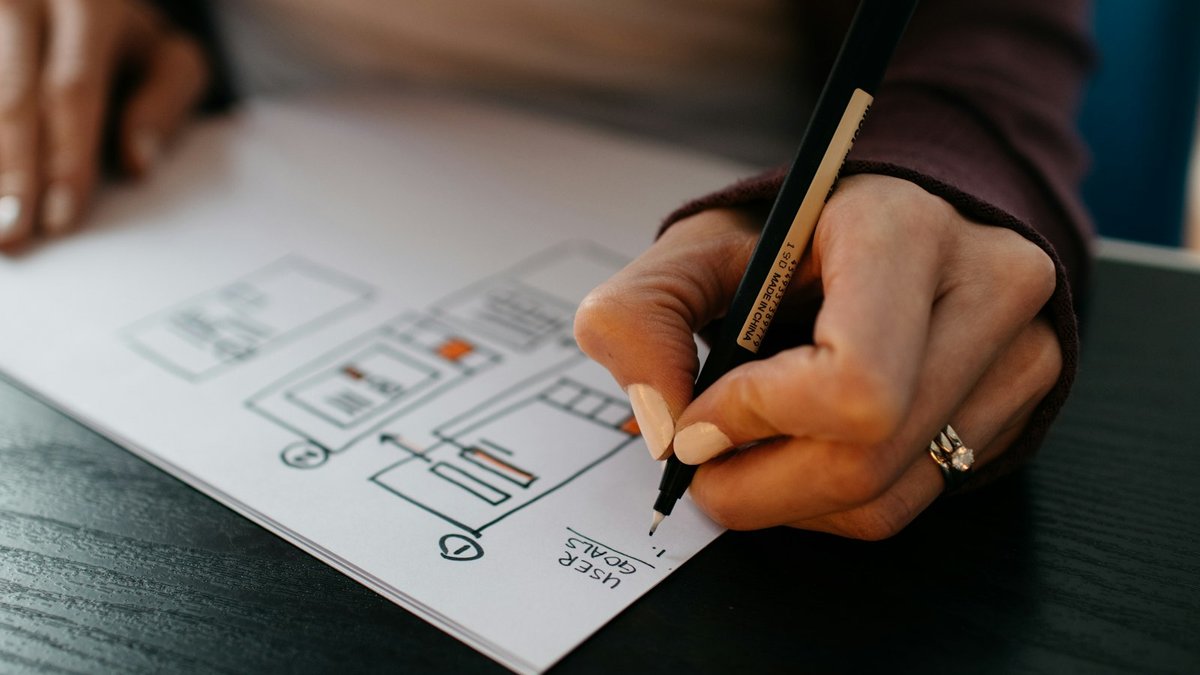 Microsoft Clarity: guida completa allo strumento gratuito di heatmap 6 Mani di una UX designer che disegnano il wireframe di una pagina web per ottimizzare le conversioni